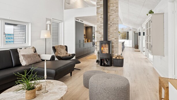 Un salon moderne avec une cheminée, un canapé, des poufs et une table basse.