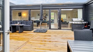 Une terrasse extérieure moderne équipée d’une table de billard, d’un coin salon et d’un barbecue.