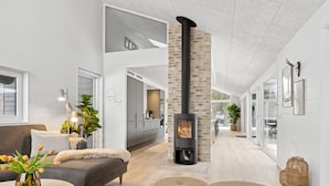 Un intérieur moderne avec une cheminée, un canapé, des poufs et un coin repas.