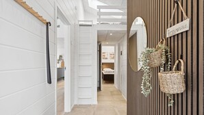 Un couloir avec un mur en bois, un lit et une porte blanche.
