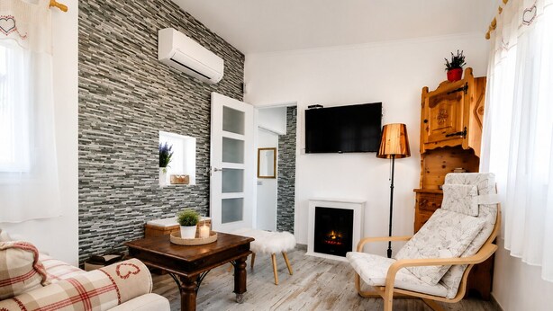 A living room with a stone wall, a fireplace, a TV, and a wooden chair.