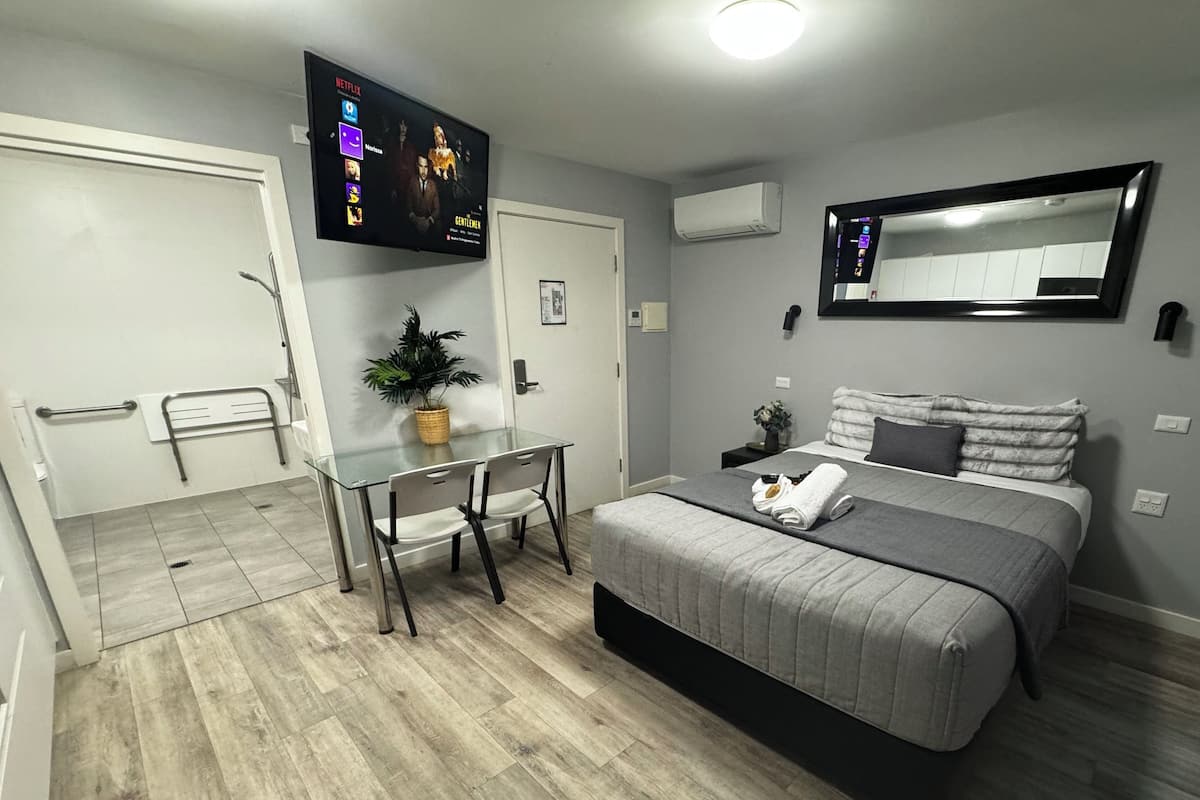 Camera moderna con un letto, comodino e TV a parete che mostra Netflix.