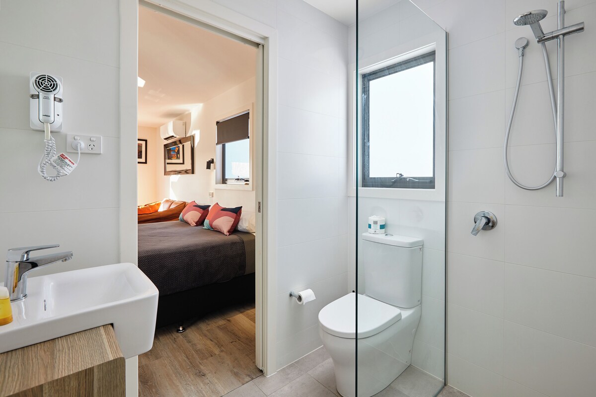 A modern bathroom with a glass shower enclosure, a white sink, and a toilet.