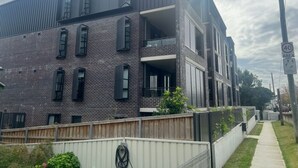 Ein modernes, mehrstöckiges Gebäude mit Backsteinfassade, großen Fenstern und einem Balkon.