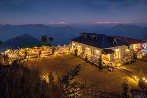 A well-lit hotel with multiple rooms, a spacious outdoor area, and a view of the surrounding mountains. - amã Stays & Trails Barefoot Bungalow, Dhanaulti (Dehradun)