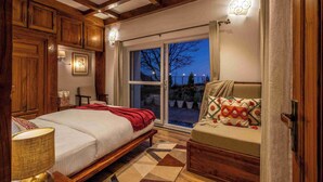 Une chambre à coucher comprenant un lit, un canapé, des meubles en bois, une fenêtre et une porte.