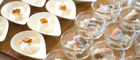A variety of small dishes with rice and fish, arranged on a wooden table.