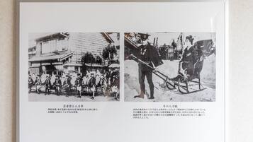 A framed historical photograph with two scenes: one of a group of people in traditional attire near a building, and another of a person pulling a sled.