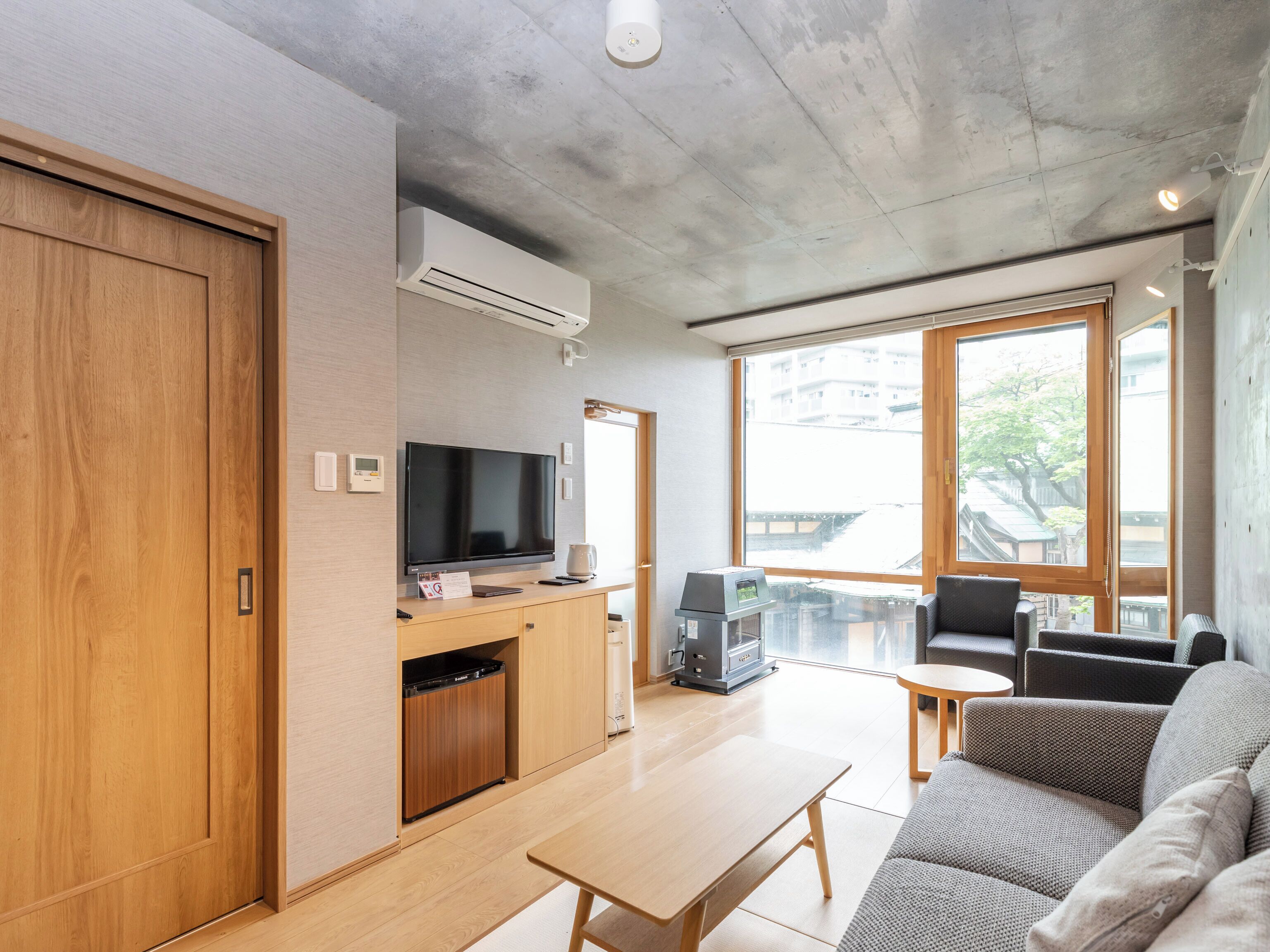Un salon moderne comprenant un canapé, une table basse, un téléviseur et une petite kitchenette.