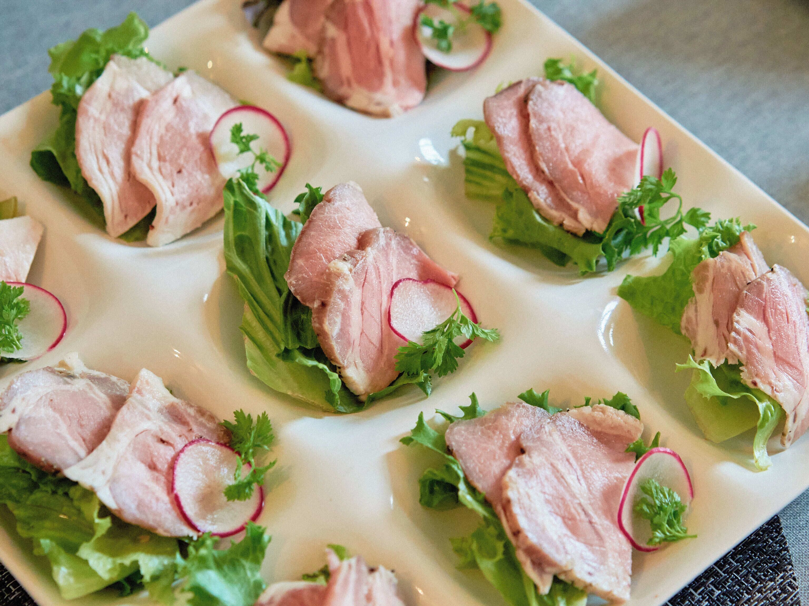 A plate of food with sliced meat, lettuce, and radish slices.
