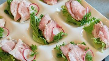 A plate of food with sliced meat, lettuce, and radish slices.