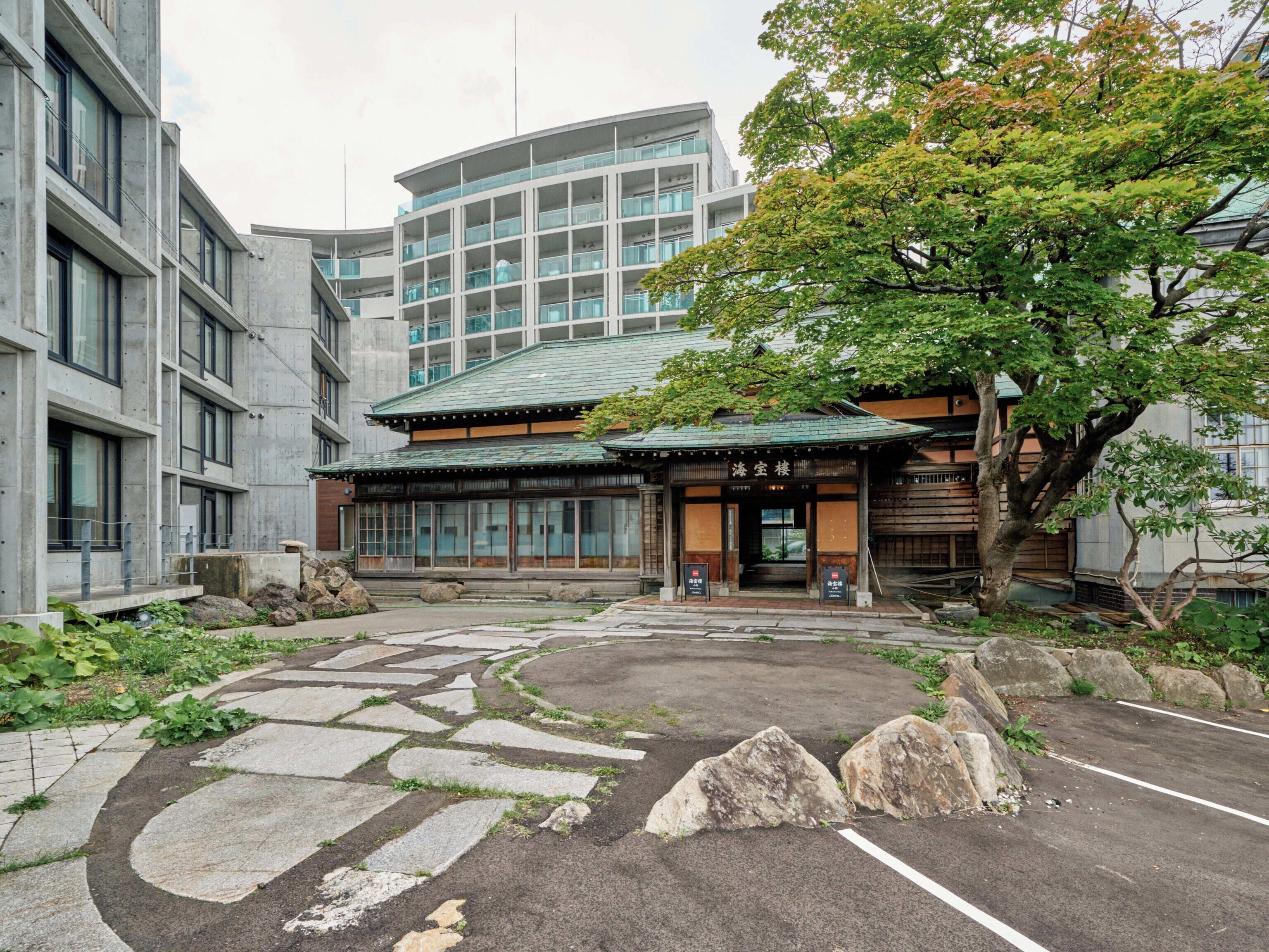 A traditional Japanese building with a curved roof, large windows, and a stone pathway leading to the entrance.