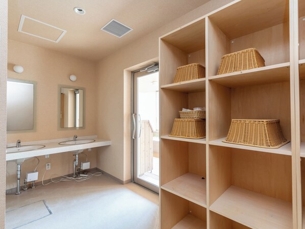 Une salle de bain moderne avec deux vasques, un miroir et des paniers en osier placés sur des étagères.