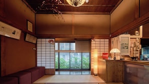 Ein traditioneller japanischer Raum mit Tatami-Böden, einem Empfangstresen und Blick auf Grünflächen.