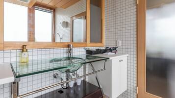 A modern bathroom with a glass sink, wooden vanity, and a large mirror.