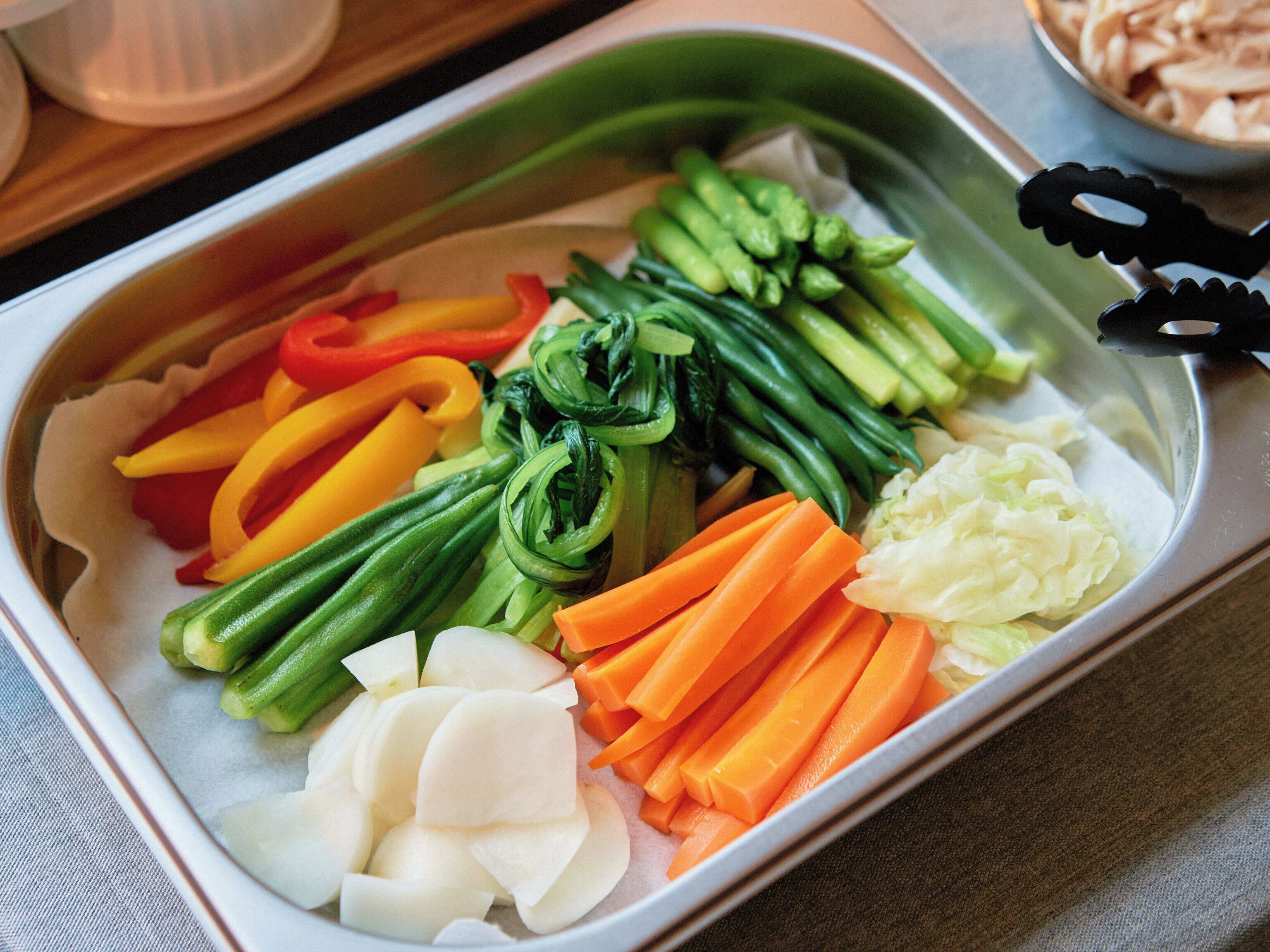 A tray of assorted vegetables including carrots, bell peppers, and cabbage.