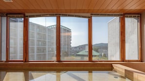 Ein geräumiger Innenbereich mit großen Fenstern, Fliesenboden und Blick auf die umliegenden Gebäude.