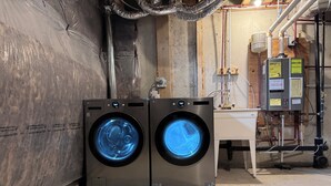 Two front-loading washing machines in a utility room with exposed ductwork and a water heater. - Elegant Townhome in Prestigious Woodbridge Estate, Vaughan (Selena) (Vaughan)