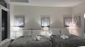 A hotel room with two beds, each with a patterned bedspread, white pillows, and a bedside lamp. There are three abstract paintings on the walls, and a window with blinds on the left side. - Elegant Townhome in Prestigious Woodbridge Estate, Vaughan (Selena) (Vaughan)