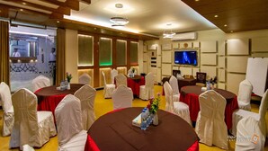 A conference room with round tables, white chairs, and a television screen. - Hotel Beach Way (Cox's Bazar)