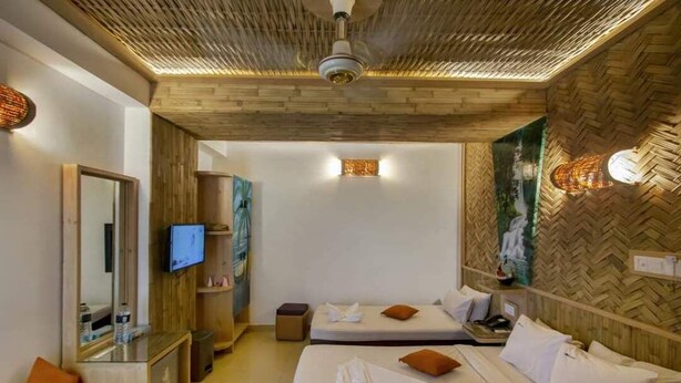 A hotel room with two beds, a TV, a mirror, and a wooden ceiling. - Hotel Beach Way (Cox's Bazar)