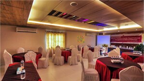 A conference room with tables and chairs, a projector screen, and a banner on the wall. - Hotel Beach Way (Cox's Bazar)