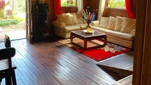 A wooden interior with a sofa, a coffee table, and a dining table. - Rancho Fernandez (Jarabacoa)