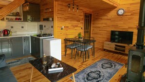 Ein gemütliches Blockhauss-Interieur mit einer Küche, einem Essbereich und einem Kaminofen.