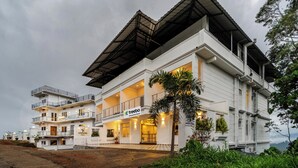 A multi-story hotel with a flat roof and balconies. - Treebo Windsong Resort Munnar (Devikolam)