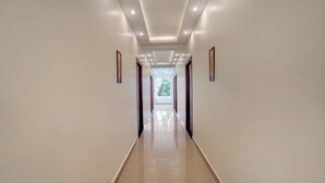 A long, well-lit hallway with a polished floor and recessed lighting. - Treebo Windsong Resort Munnar (Devikolam)