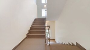 A staircase with a metal handrail, leading to a landing with a window. - Treebo Windsong Resort Munnar (Devikolam)