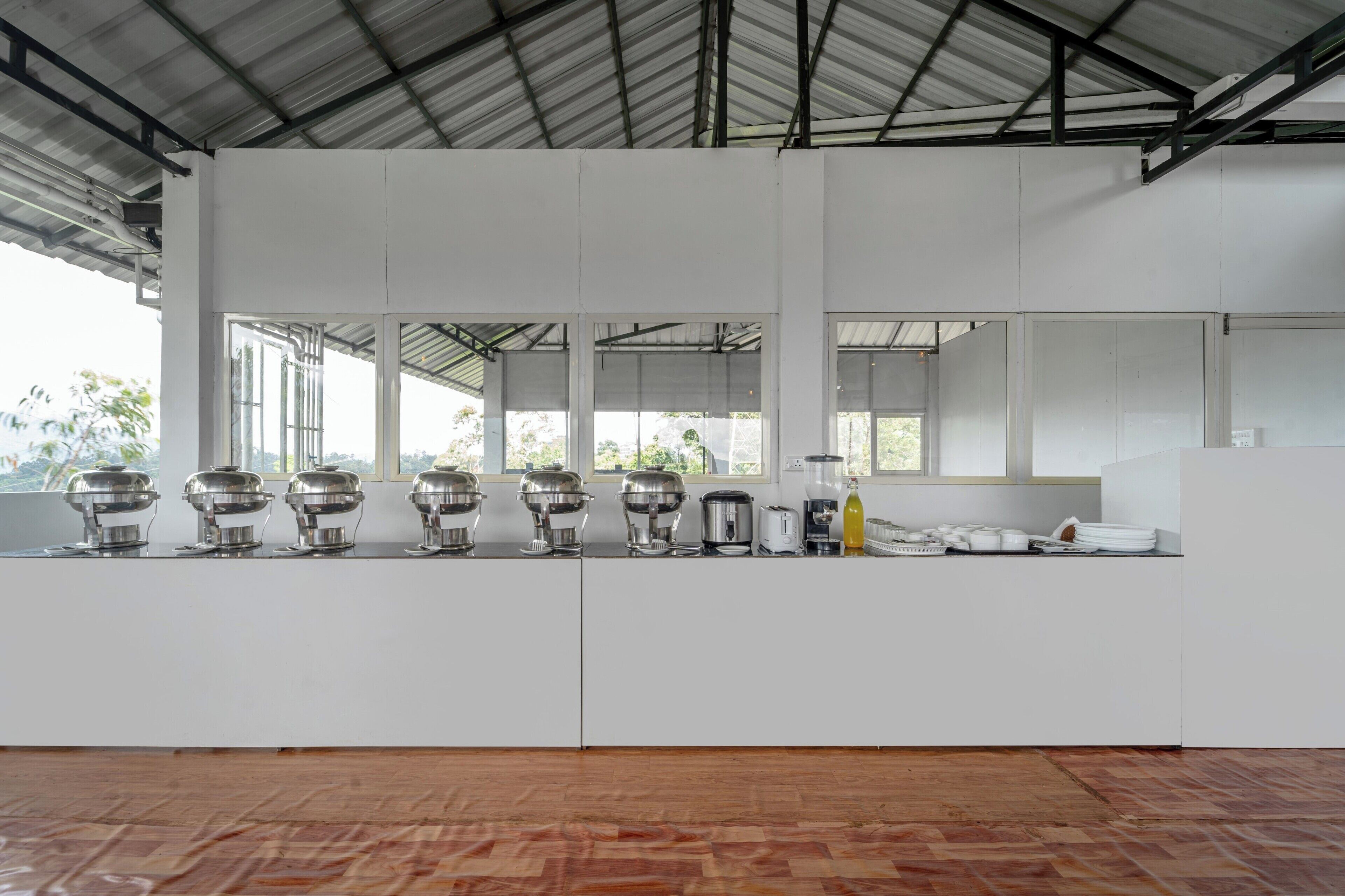 Una cocina moderna con armarios blancos, piso de madera y techo de metal.
