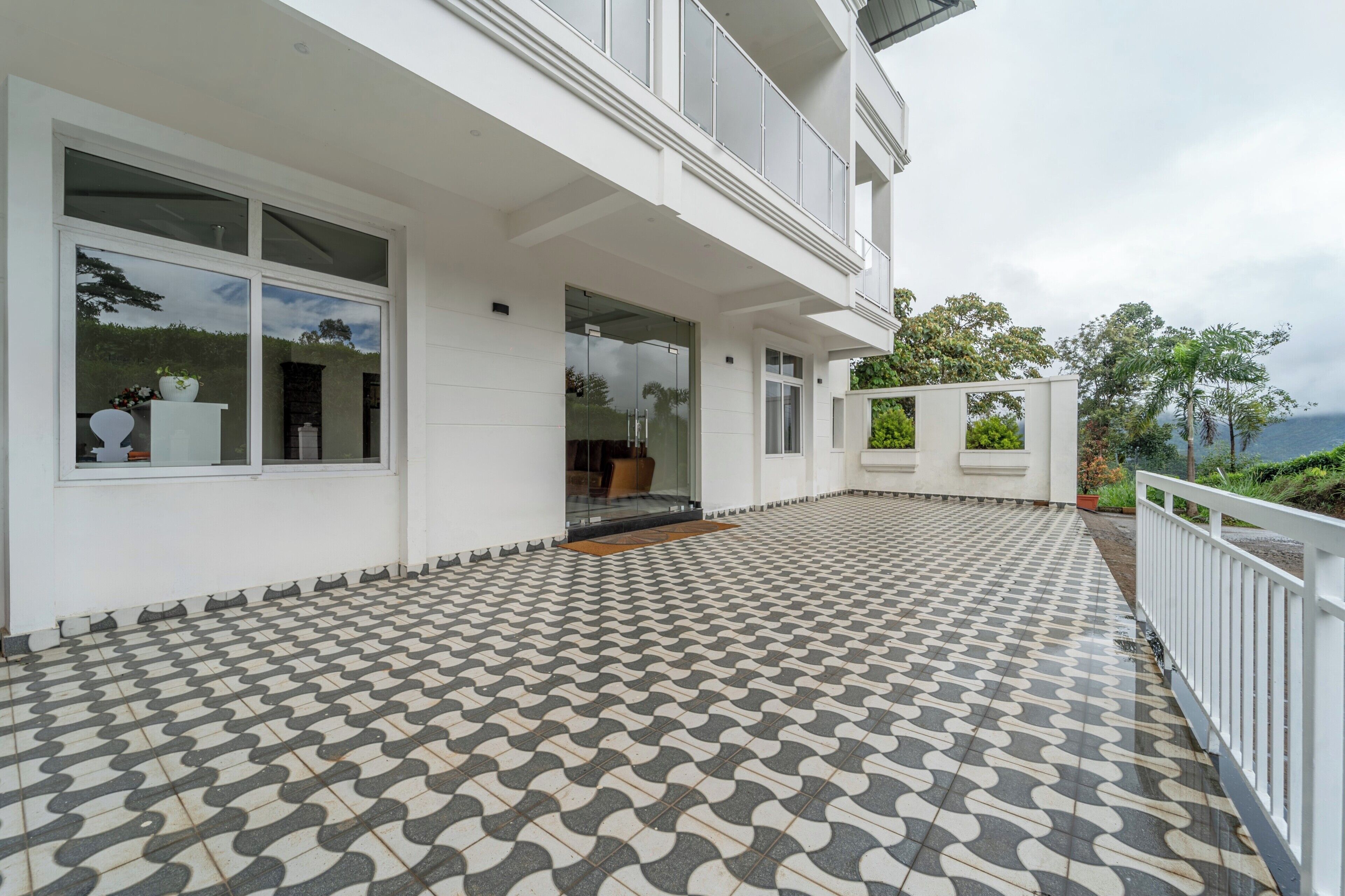 A modern building with a tiled patio, large windows, and a view of the ocean.