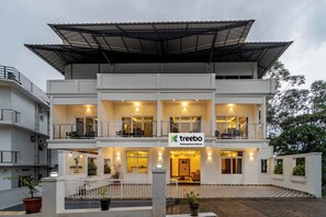 Un hôtel à plusieurs étages, doté d’un toit plat, de balcons et d’une enseigne indiquant « Treebo Windsong Resort Munar ».