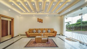 A modern lobby with a large sofa, a coffee table, and a patterned rug. - Treebo Windsong Resort Munnar (Devikolam)