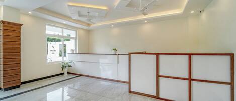 A spacious lobby with a polished marble floor, a reception desk, and a large window offering a view of the outdoors.