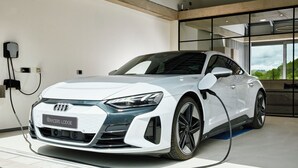 A white Audi R8 charging at a station labeled "Racers Lodge." - Racers Lodge "Grand Prix" with lifting platform and double garage, near Nürburgring  (Bermel)