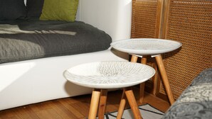 A modern living room with a white sofa, green and black cushions, and two white round tables with wooden legs. - 1 Bedroom Apartment in Lochau (Lochau)