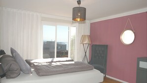 A bedroom with a bed, a chair, a lamp, and a round mirror on the wall. - 1 Bedroom Apartment in Lochau (Lochau)