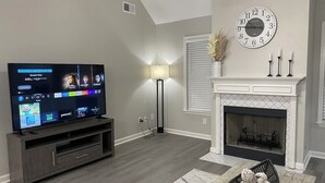 Un salon équipé d’un téléviseur à écran plat, d’une cheminée, d’une horloge et d’une lampe.