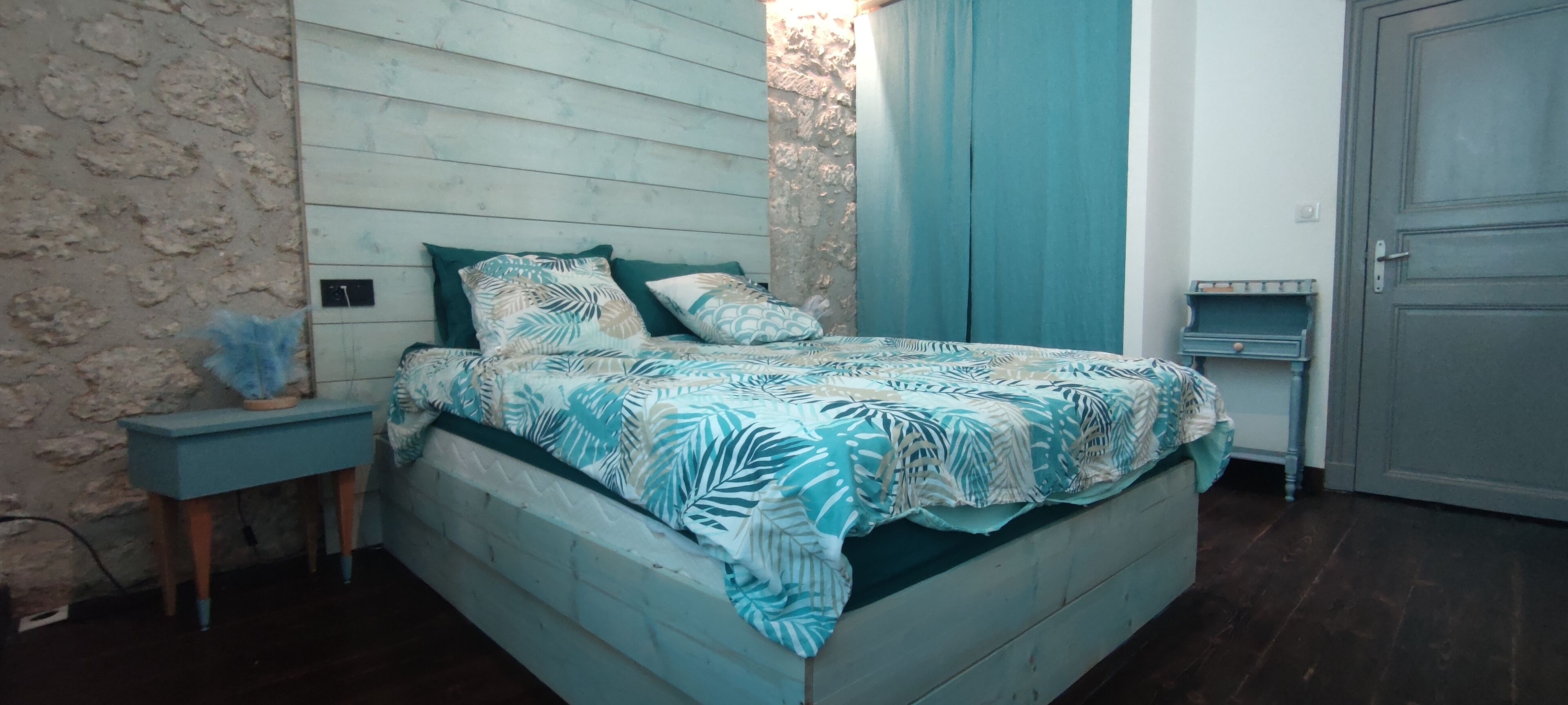 A bedroom with a bed, a nightstand, a dresser, and a door.