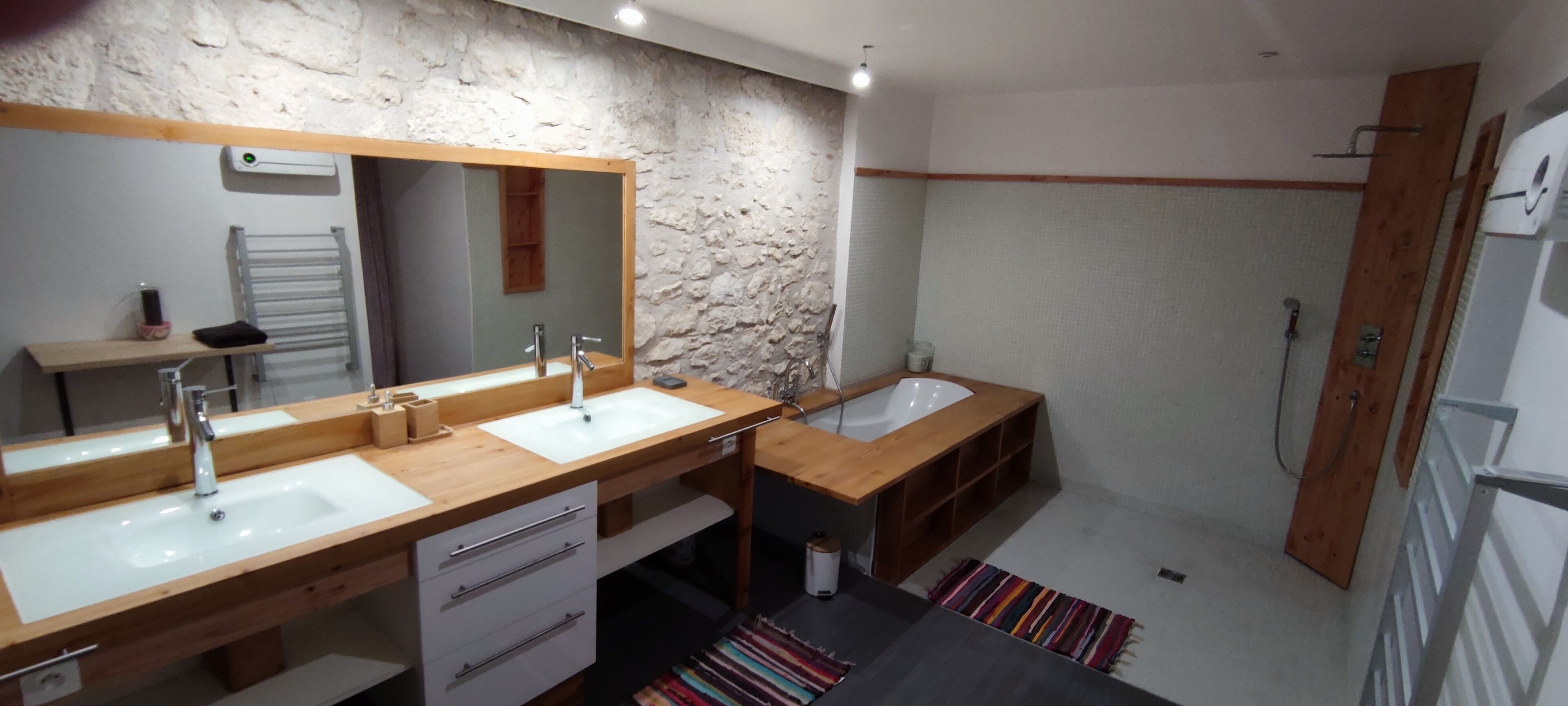 A modern bathroom with two sinks, a large mirror, a bathtub, and a shower.