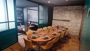 Zona de menjador amb una taula de fusta llarga preparada per a dinar, envoltada de cadires grogues.