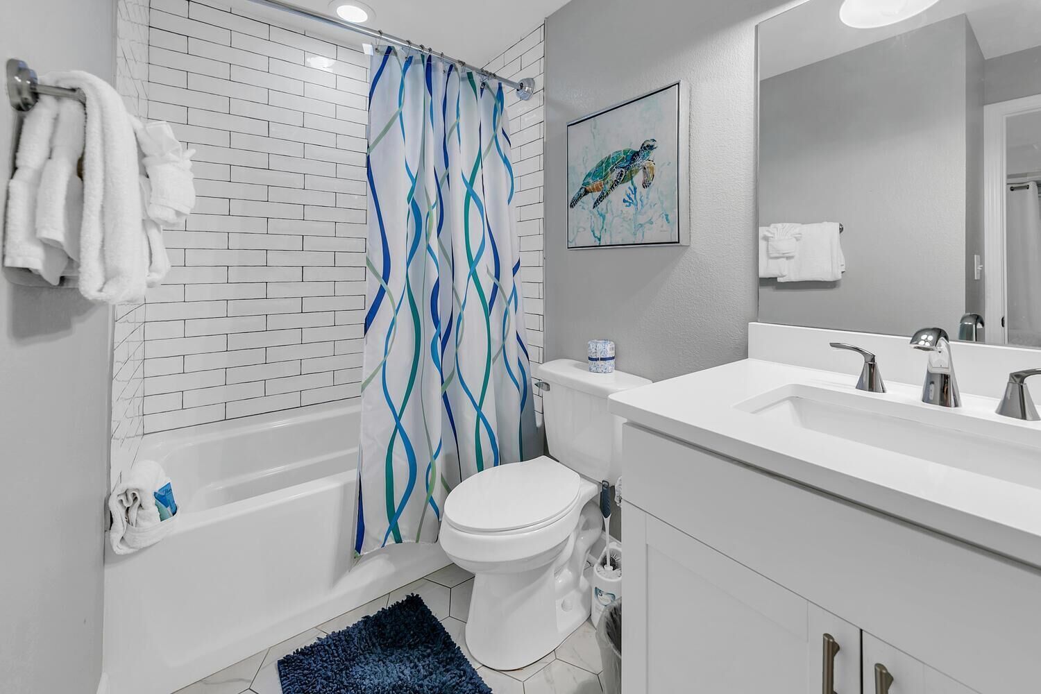 A modern bathroom with a white bathtub, a toilet, and a sink with a mirror.
