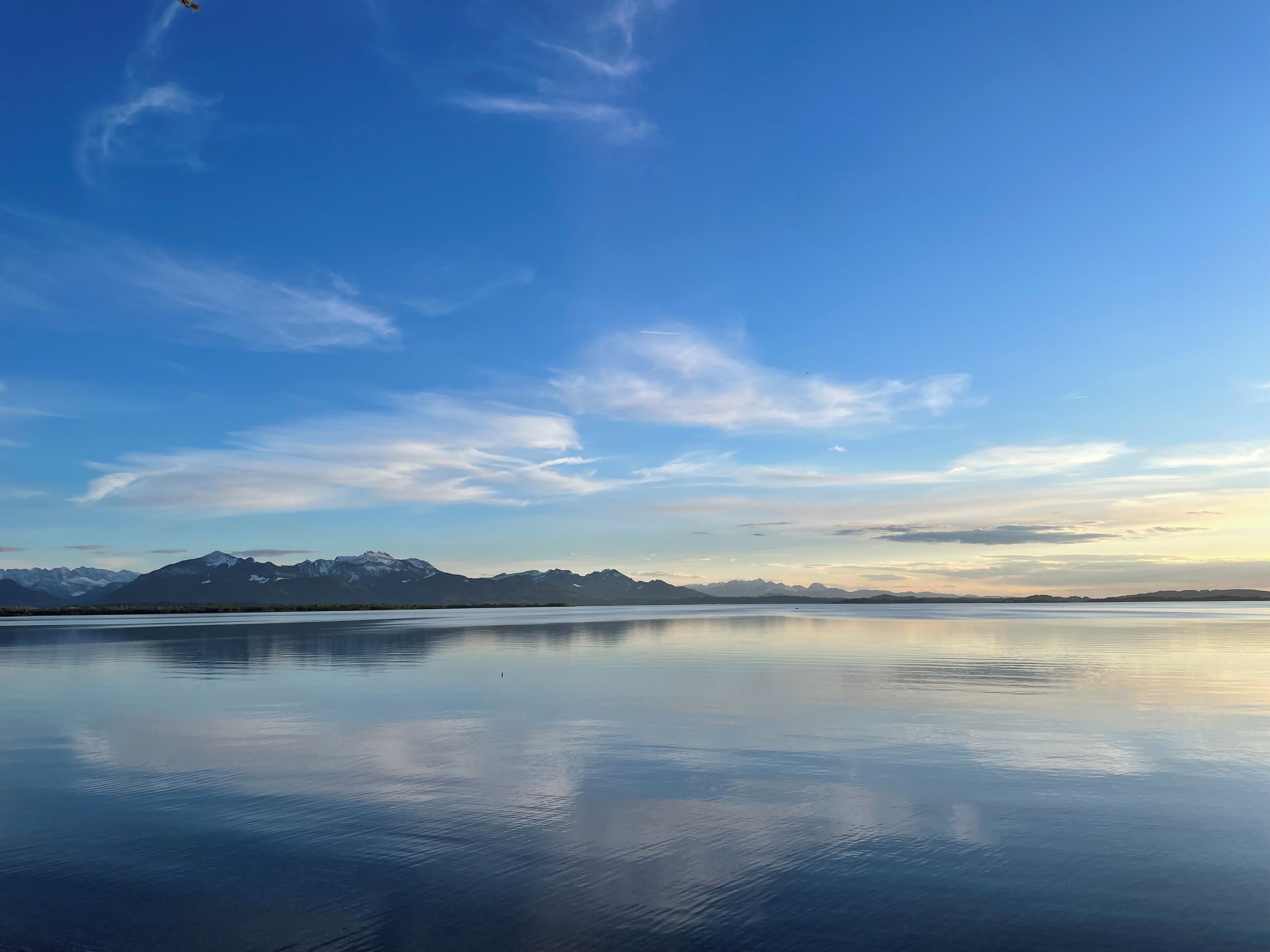 A calm lake with mountains in the background and a clear sky.