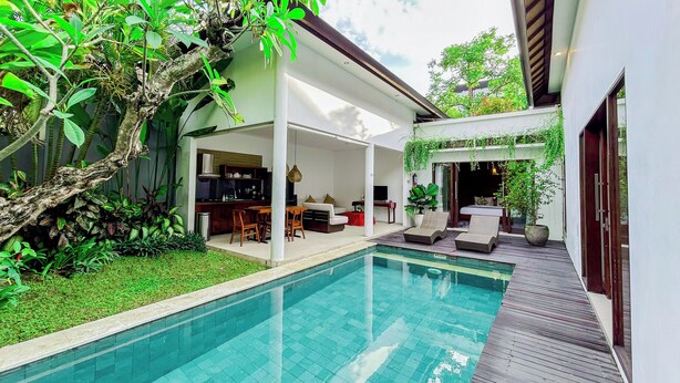 A modern outdoor pool area with a kitchen and living space, surrounded by lush greenery. - Kamboja Villa Umalas by Premier  (Kerobokan)