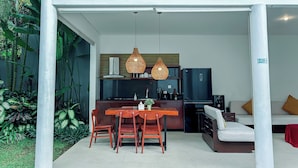 A modern kitchen with a black refrigerator, wooden chairs, and a dining table. - Kamboja Villa Umalas by Premier  (Kerobokan)