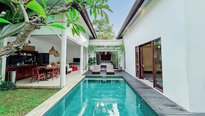 A modern house with a swimming pool, a dining area, and a living room with a TV. - Kamboja Villa Umalas by Premier  (Kerobokan)