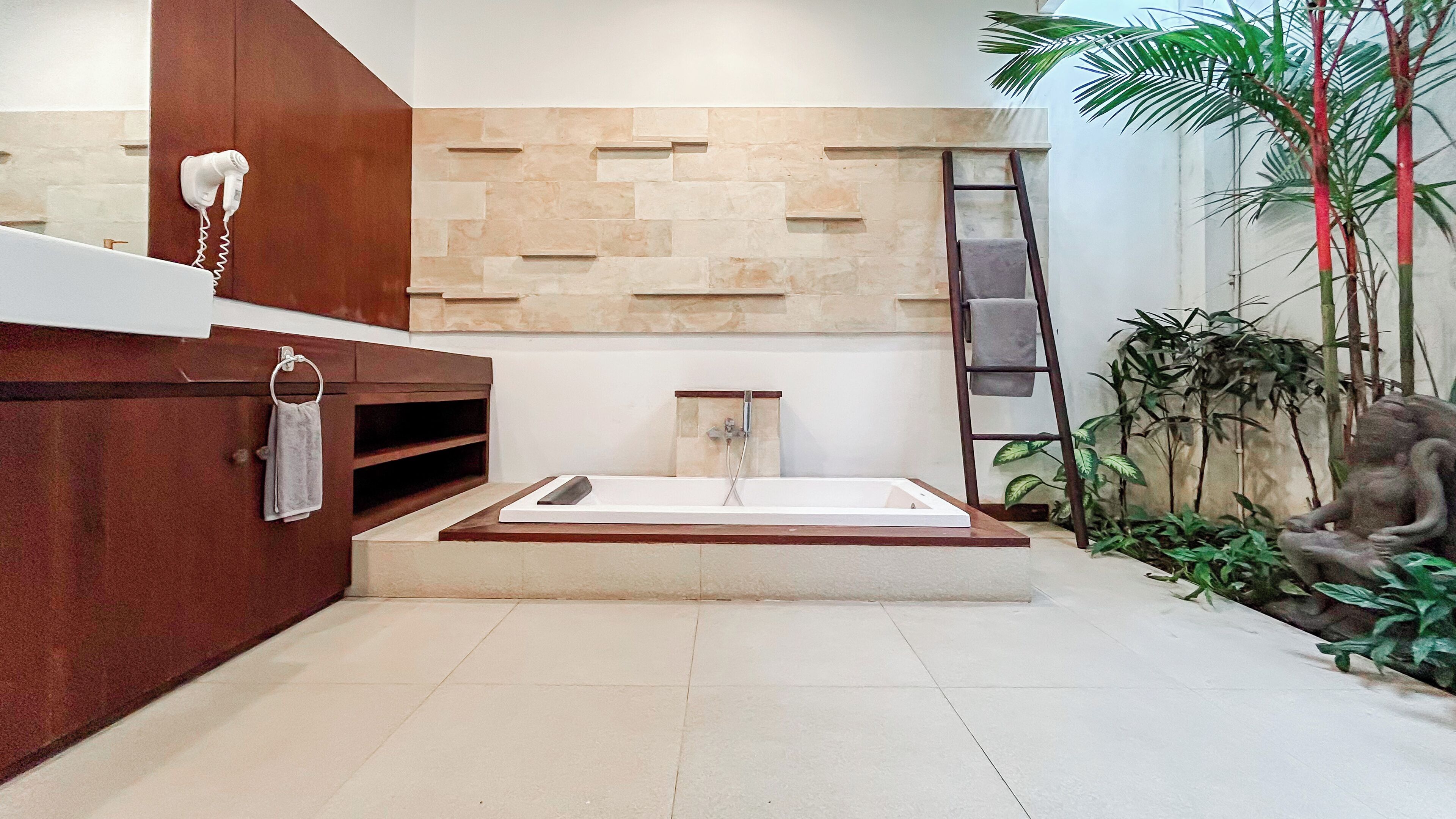 A modern bathroom with a large bathtub, a wooden vanity, and a stone wall.