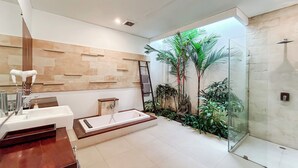 A modern bathroom with a glass shower enclosure, a built-in sink, and a decorative wall with plants. - Kamboja Villa Umalas by Premier  (Kerobokan)